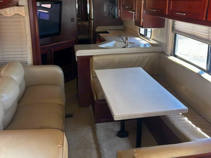 RV rental interior showing a comfortable living area with sofa, kitchen, and dining booth.. Forest River Berkshire 2011