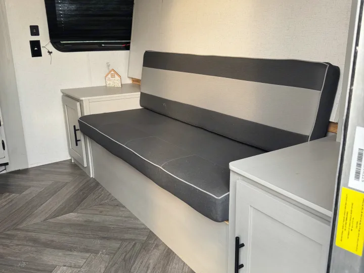 RV rental interior: cozy gray sofa with light cabinets, charging ports, and herringbone floor. Perfect for your next trip!. Forest River Wildwood FSX Toy Hauler 2021