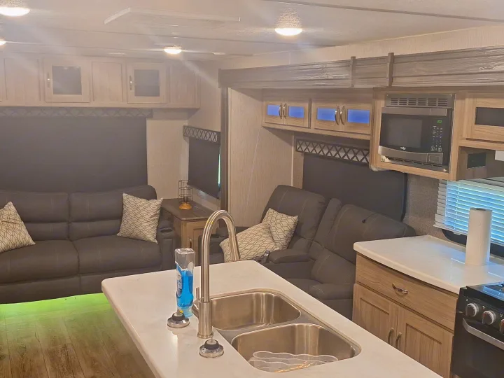 Well-equipped RV rental kitchen and living area with island, microwave, comfy couches, and mood lighting.. Coachmen Liberty express 2021