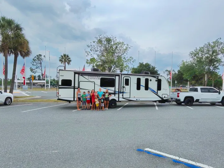 An rv rental journey begins! A family of 8 poses proudly with their Freedom Express travel trailer and truck.. Coachmen Liberty express 2021