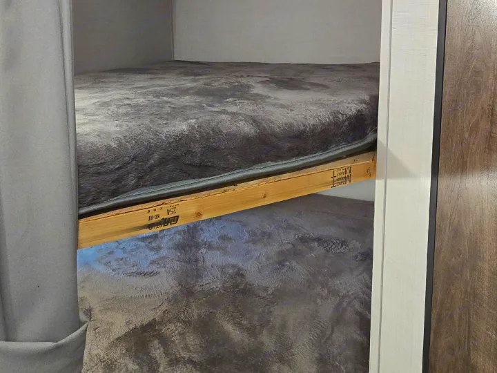 Cozy bunk beds with fuzzy gray blankets in an RV rental, providing a compact sleeping area for adventurers.. Gulf Stream Ameri-Lite 2024