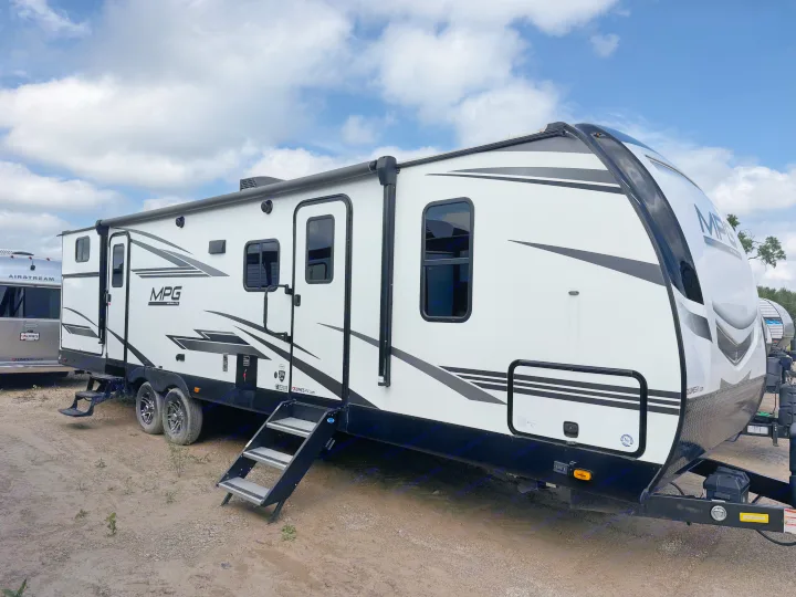 A white MPG Ultra-Lite travel trailer, perfect for RV rental and camping trips, on a dirt lot. An Airstream is visible nearby.. Cruiser RV MPG Ultra Lite 2022