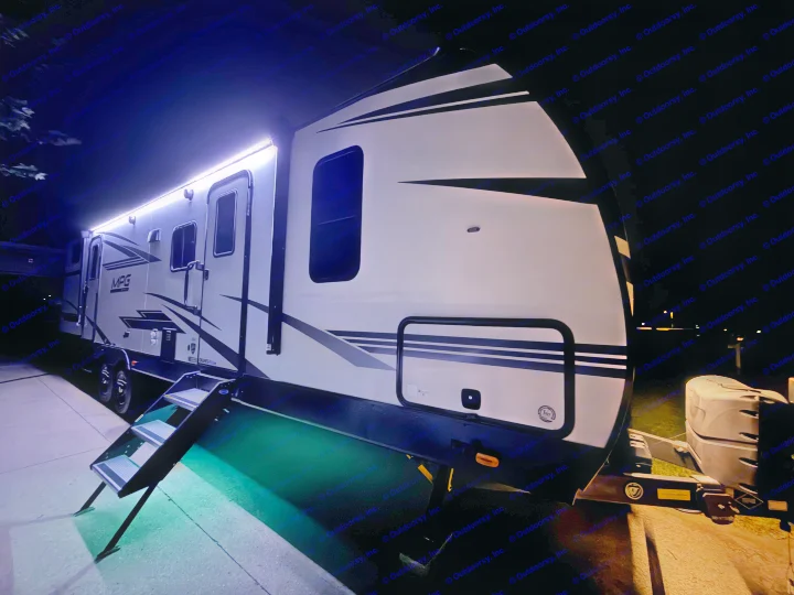 Experience night camping with this illuminated rv rental. A modern white RV with vibrant LED awning lights and entrance steps.. Cruiser RV MPG Ultra Lite 2022