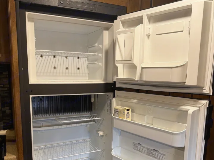 Open, clean RV rental refrigerator and freezer, empty except for baking soda. Ready for your travel food storage.. Forest River T27TDSS 2017