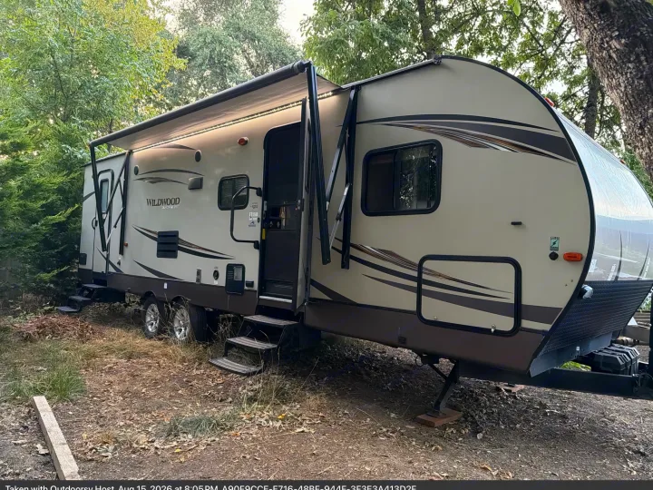 Wildwood travel trailer RV rental parked in a wooded area, awning out with lights. Perfect for an outdoorsy camping trip.. Forest River T27TDSS 2017