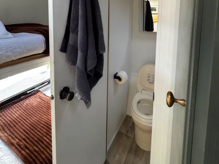 RV rental: View into a compact bathroom (toilet, mirror) and adjacent sleeping area with bunk beds and blankets.. Sportsmen Classic 2014