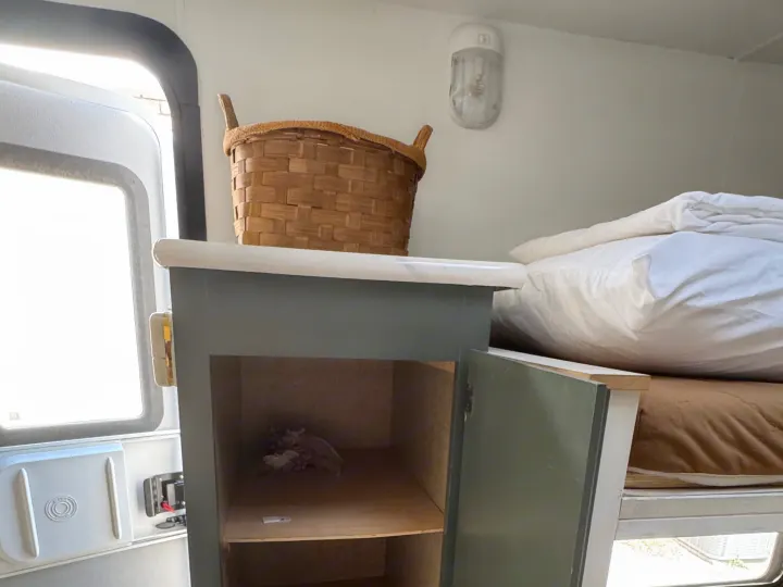RV rental interior: A tall open cabinet reveals shelves, beside cozy bunk beds and a door leading outside.. Sportsmen Classic 2014
