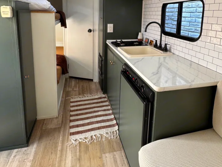 Stylish RV rental with a dark green kitchen, white marble counter, subway tile, and bunk beds.. Sportsmen Classic 2014