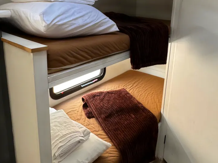 Compact bunk beds in an RV rental, offering cozy sleeping space with a window view and comfortable bedding.. Sportsmen Classic 2014