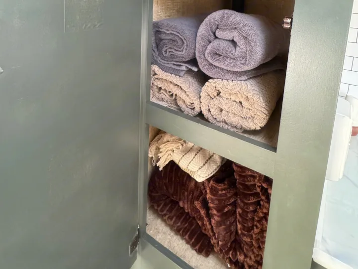 RV rental: Compact cabinet with neatly rolled and folded white, grey, and brown towels and blankets, organized for guest comfort.. Sportsmen Classic 2014