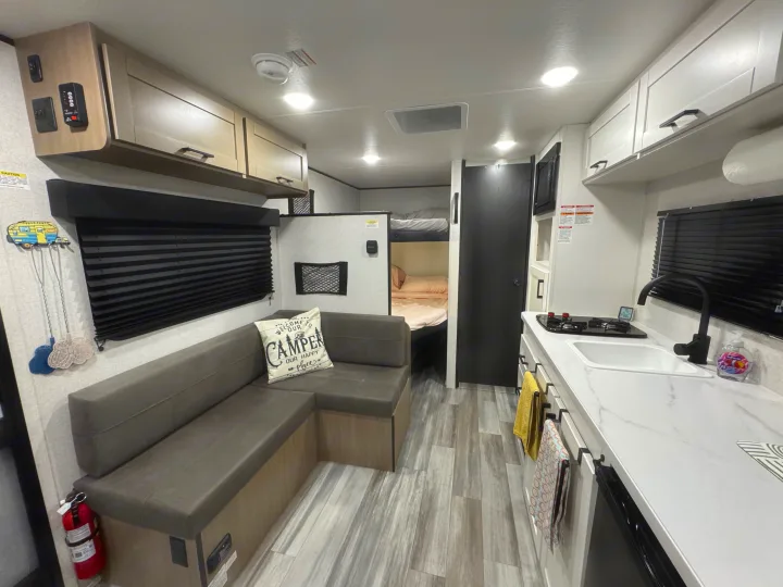 Inside a modern RV rental: view of the compact living area, kitchen with sink/stove, and bunk beds in the rear.. Jayco Jay Flight SLX Sport Edition 2026