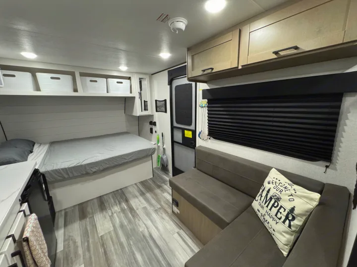 Bright RV rental interior features a comfy bed, L-shaped sofa, and kitchen counter, all in light, modern tones.. Jayco Jay Flight SLX Sport Edition 2026