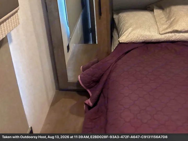 Comfortable RV rental bedroom featuring a purple quilted bed, pillows, and a nearby mirror for a cozy interior.. Forest River Salem 2022
