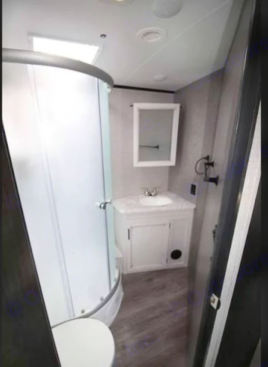 Inside an RV rental bathroom: compact corner shower, vanity, sink, and toilet with modern finishes.. Jayco White Hawk 2021