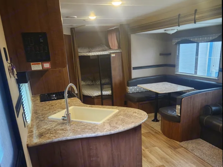 RV rental interior featuring a kitchen with sink/stove, dinette booth, and bunk beds. Perfect for your next adventure!. Aspen Trail Aspen Trail Trailer 2018