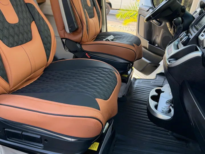 Inside an RV rental: two-tone brown & black custom quilted seats, dash, steering wheel, & hand sanitizer bottle.. Dodge 3500shc 2021