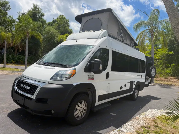 White pop-top Ram ProMaster camper van RV rental, parked under sunny skies with palm trees. Ready for adventure!. Dodge 3500shc 2021