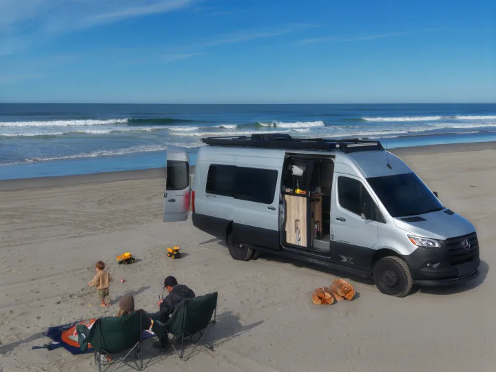 Family enjoys a beach day with their Sprinter camper van, perfect for an rv rental adventure by the ocean.. Airstream Interstate 2022