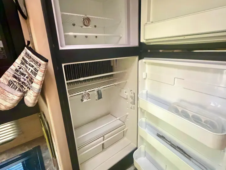 Spacious, empty RV rental refrigerator with freezer and shelves, sparkling clean and ready for your provisions.. Thor Four Winds 2023