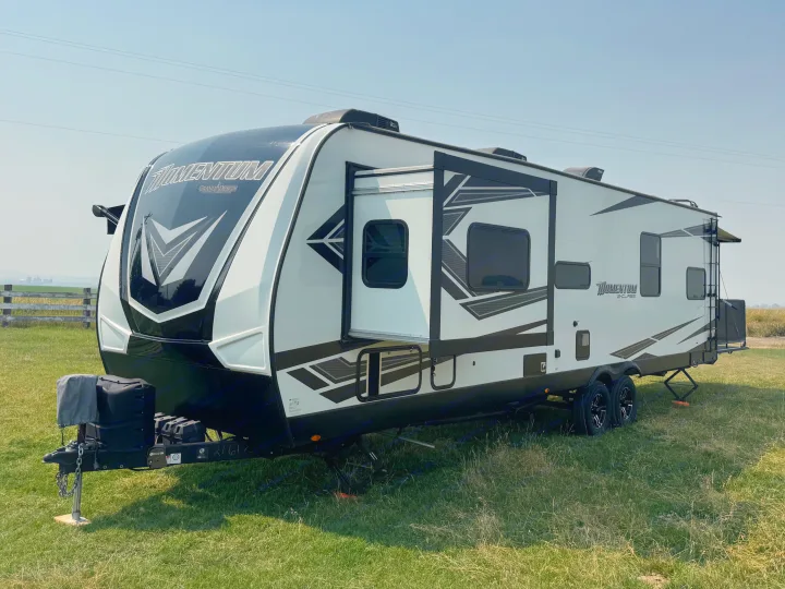 Grand Design Momentum travel trailer RV rental with slide-out extended, parked in a green field, ready for your trip.. Grand Design Momentum 2022