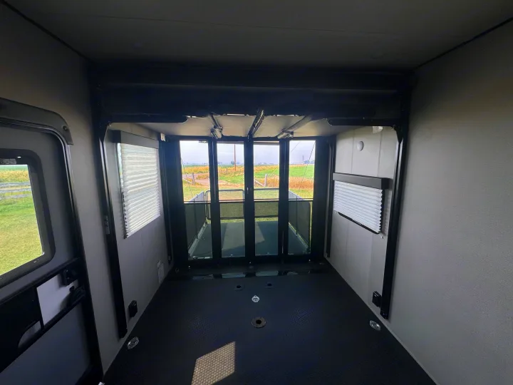 Toy hauler RV rental cargo space featuring a durable floor with tie-downs, large rear glass doors, and scenic outdoor views.. Grand Design Momentum 2022