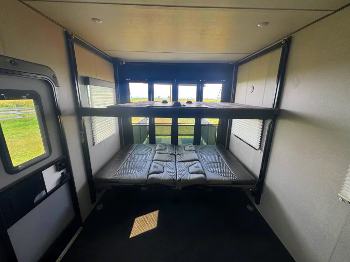 Inside an RV rental: a modern toy hauler interior with adjustable bunk beds and a scenic view from the rear windows.. Grand Design Momentum 2022