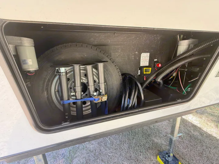 RV rental's front storage bay showing spare tire, stabilizer jacks, coiled shore power cable, and electrical controls.. Forest River Sabre - 36DBB 2027