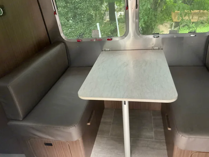 This RV rental interior features a cozy dinette with bench seating and a table, perfect for meals or relaxing during your travels.. Airstream Caravel 2020