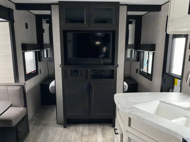 This RV rental interior showcases a TV entertainment center, dinette, kitchen sink, and cozy sleeping areas.. Jayco Jay Flight SLX 2022