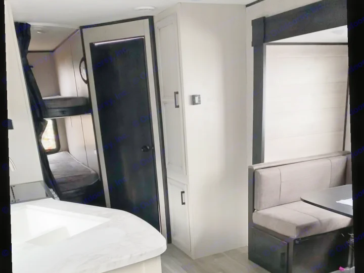 This RV rental interior features bunk beds, a kitchen counter, dinette seating, and ample storage, perfect for travel.. Jayco Jay Flight SLX 2022