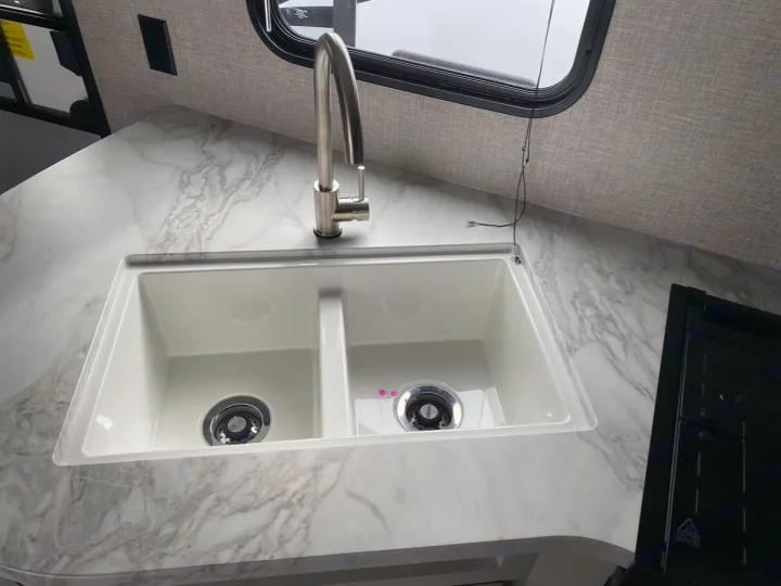 RV rental kitchen: white double sink with a modern brushed metal faucet on a marble-patterned counter. Includes a window & stovetop.. Jayco Jay Flight SLX 2022