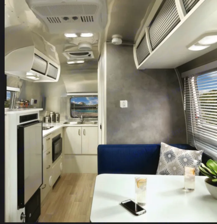 Step into comfort with this modern **rv rental** interior. Features a compact kitchen, cozy dining booth, and bright windows.. Airstream Bambi 2022