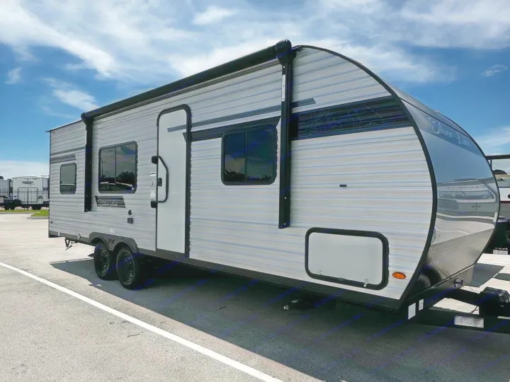 Sleek travel trailer, ideal for your next RV rental adventure, parked outdoors under a bright blue sky with scattered clouds.. East to West Silver Lake 2024