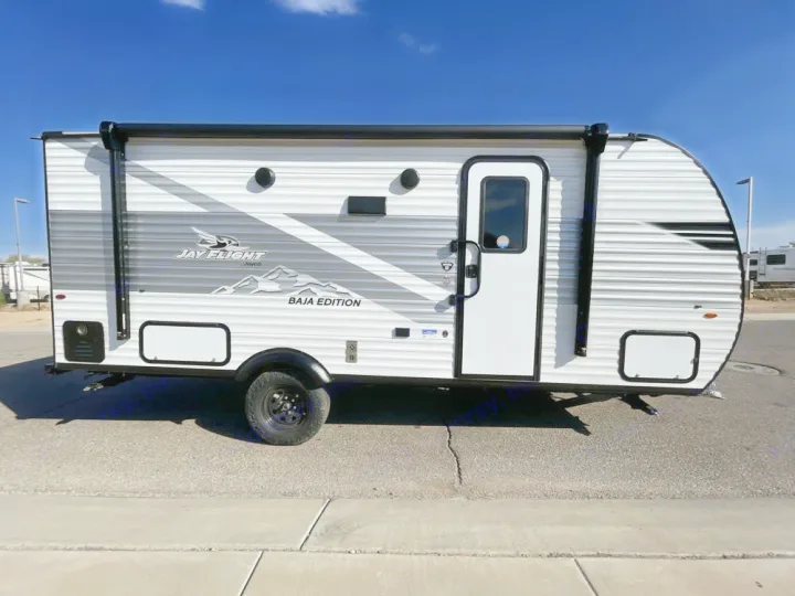This white & grey Jay Flight travel trailer (Baja Edition) is parked outdoors, an ideal RV rental for adventures.. Jayco Jay Flight SLX Baja Edition 2025