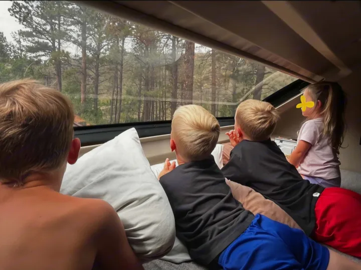 Four kids watching a forest view from their comfortable rv rental. Great family road trip adventure!. Jayco Greyhawk 2024