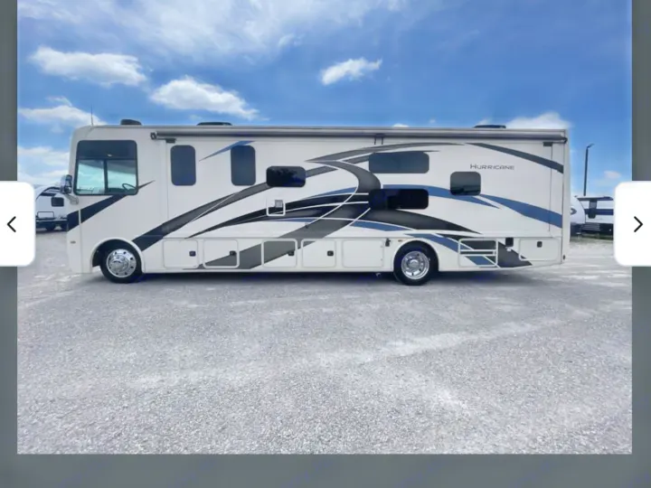 White Class A Hurricane RV rental with blue/black graphics, parked on a gravel lot under a blue sky, ready for adventure.. Thor Hurricane 2022