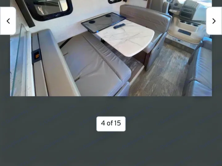 Cozy RV rental dinette and seating area with a white marble-look table and wood-style flooring, perfect for travel comfort.. Thor Hurricane 2022