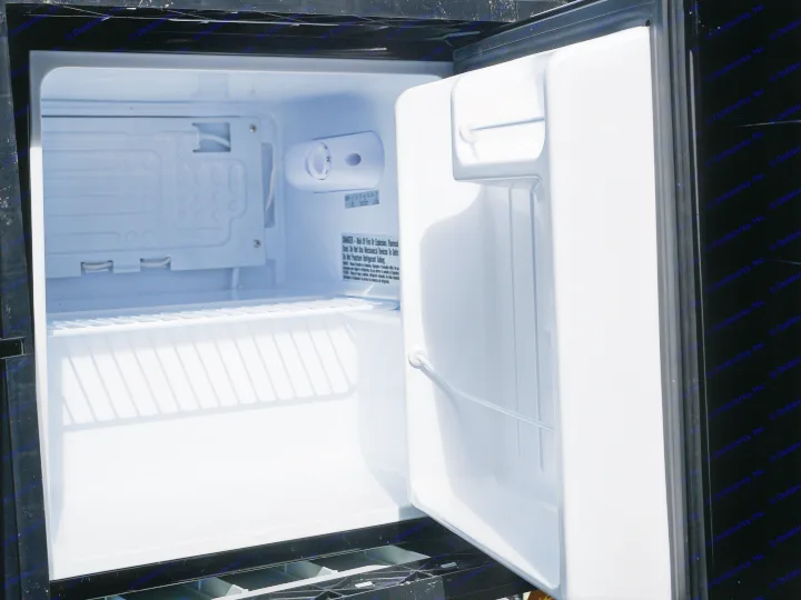 This clean, empty mini-fridge in an **RV rental** is ready for your road trip essentials. A perfect compact refrigerator for travel.. Micro-Lite Micro Camper 1987