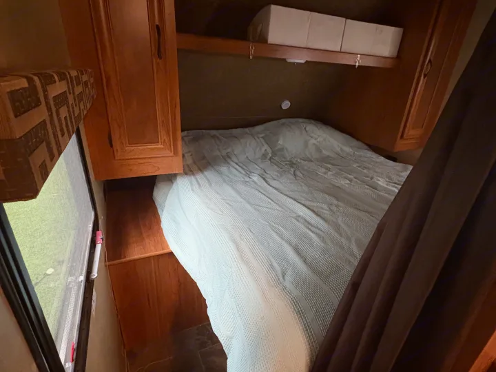 This RV rental offers a cozy bedroom with a comfortable bed, wooden storage, and a window to the outdoors.. Starcraft AR-One Maxx 2016