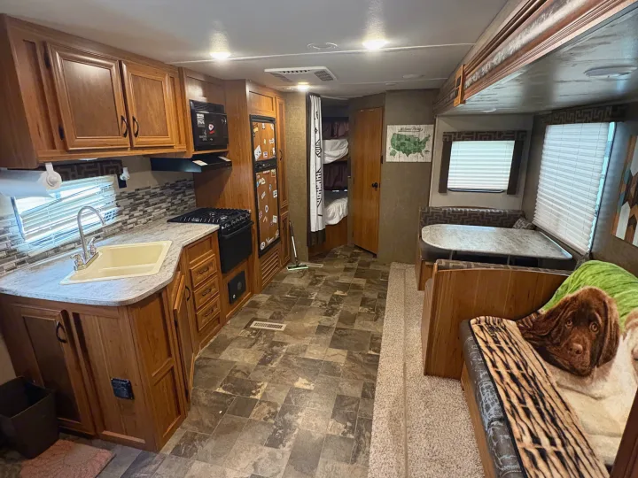 Inviting rv rental interior: full kitchen, dinette, bunk beds, and a National Parks map. Features wood cabinets & patterned floors.. Starcraft AR-One Maxx 2016