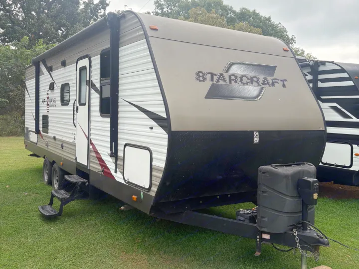 Starcraft travel trailer RV rental, with a tan front and white corrugated sides, parked on green grass.. Starcraft AR-One Maxx 2016