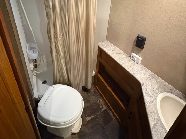 Your RV rental bathroom: a functional space with toilet, shower with striped curtain, and vanity with sink.. Starcraft AR-One Maxx 2016