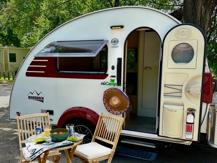 Enjoying the outdoors with this cozy nuCamp T@B teardrop RV rental, featuring an inviting table setup with drinks and snacks.. nuCamp T@B 2022