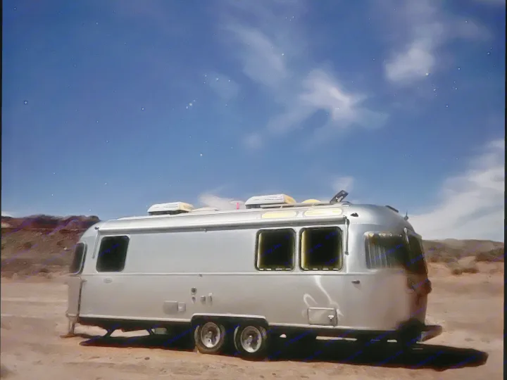 Night photo of an Airstream rv rental parked on dirt, illuminated against a dark blue, starry sky with faint clouds. Ideal for adventure.. Airstream Globetrotter 2022