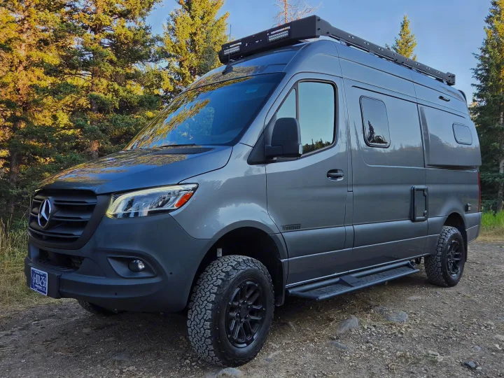 Grey Winnebago Sprinter RV rental camper van parked on a forest dirt road. Ready for Montana adventures.. Winnebago Revel 2025