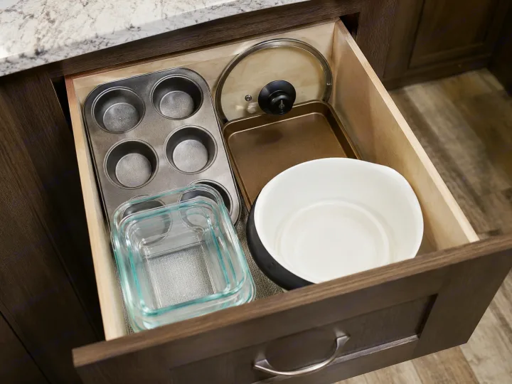 Organized kitchenware in an RV rental drawer: muffin pan, glass storage, baking tray, lid, and mixing bowl.. Forest River Surveyor 2018