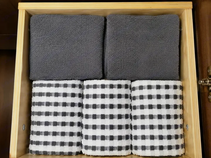 Organized RV rental drawer: Stacked gray towels and rolled checkered kitchen towels, neatly stored for your trip.. Forest River Surveyor 2018