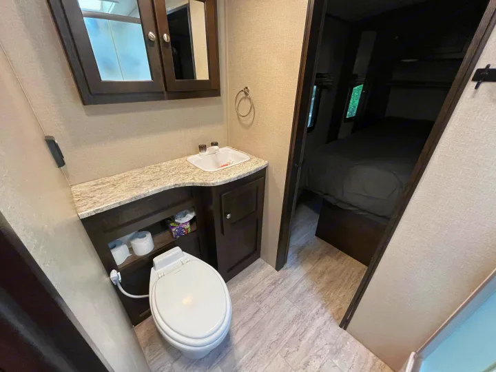 Compact rv rental bathroom with toilet, vanity, and entry to a bedroom.. Cruiser RV Shadow Cruiser 2018
