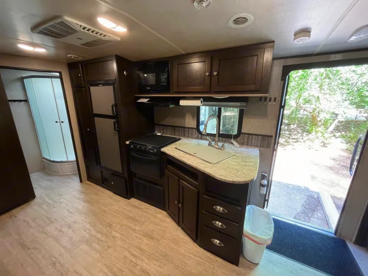 Discover this rv rental's functional kitchen with microwave, fridge, stove, sink, and nearby shower unit, designed for travel convenience.. Cruiser RV Shadow Cruiser 2018