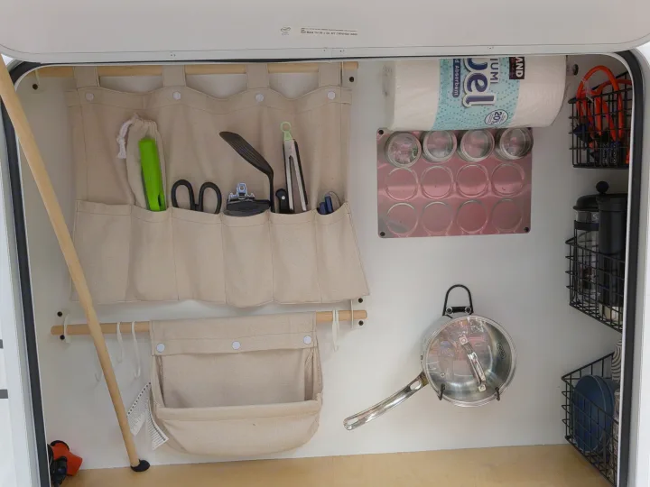 Organized RV rental kitchen: canvas tool caddies, spice rack, paper towels, hanging pot, and wire baskets for dishes. Ideal for camping.. MiniTrail Custom 2018